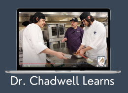  Two students and an adult in chefs coats